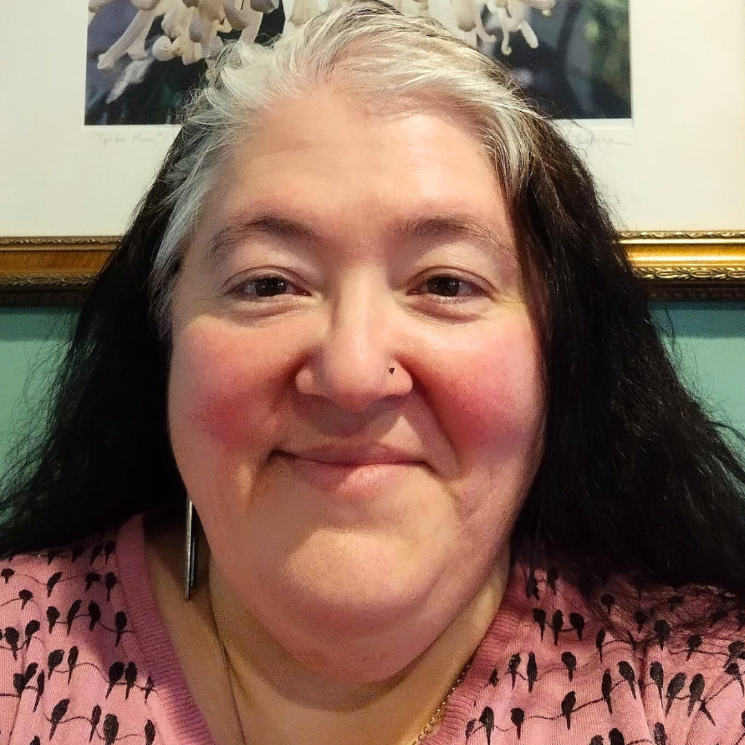 Smiling portrait of Amy Baker, who has a light skin tone, shoulder-length black hair, and white bangs.