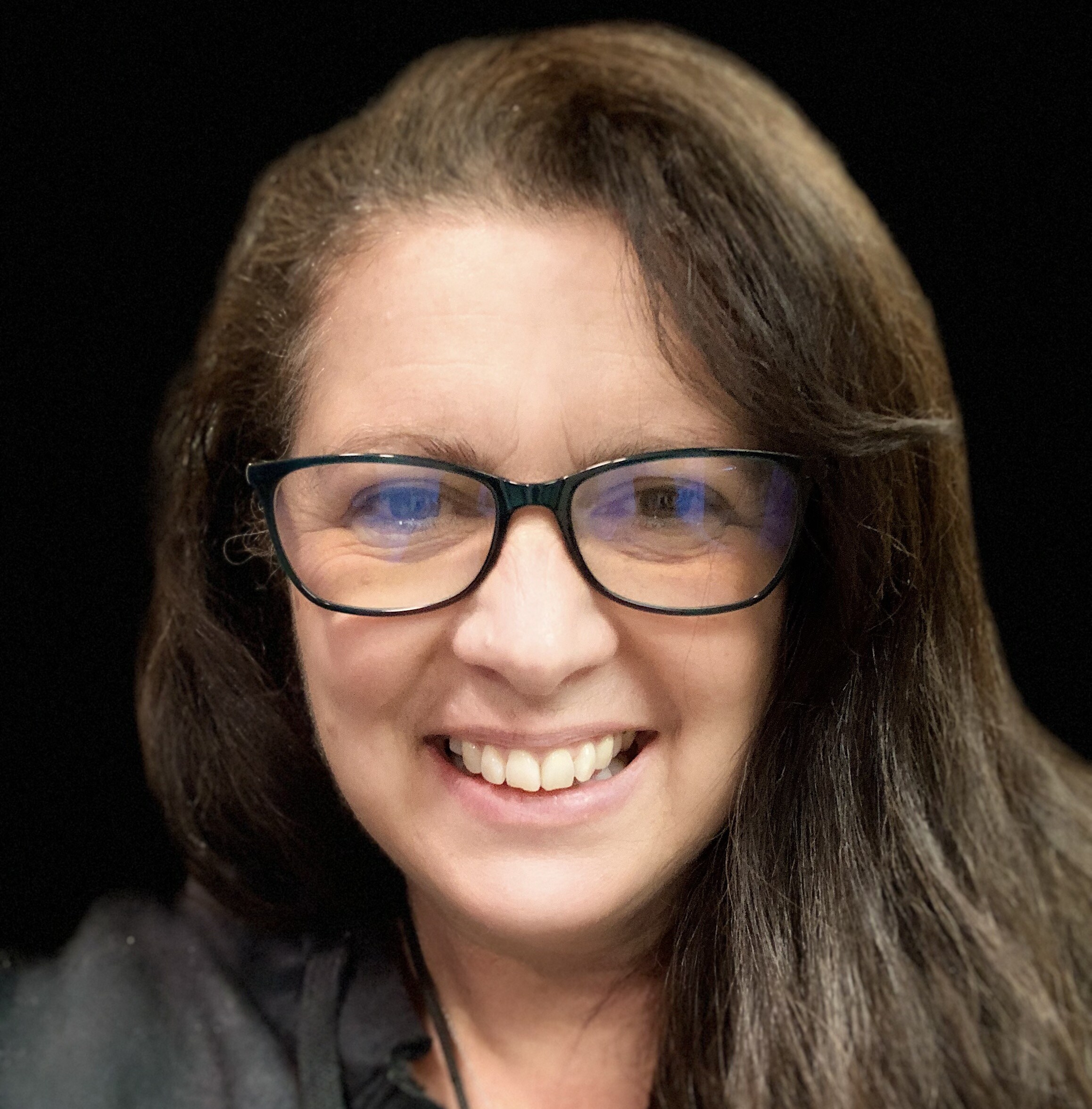 Portrait of Carrie McGee, who has a light skin tone, glasses and shoulder-length black hair.