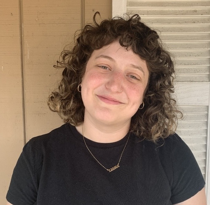 Smiling portrait of Liana Marks, who has a light skin tone and curly chin-length brown hair.