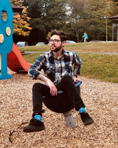 Nick Vogt, who has a light skin tone and short brown hair, sits in a spinable playground chair.