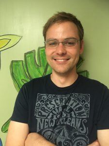 Smiling portrait of Brian Melanson, who has a light skin tone, short blond hair, and glasses.